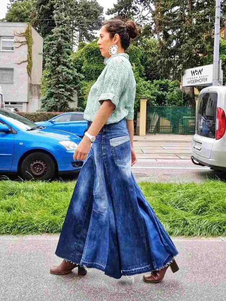 Frau trägt eine Jeansrock und eine grüne Bluse. Der Rock ist ein Upcycling aus Jeanshosen.