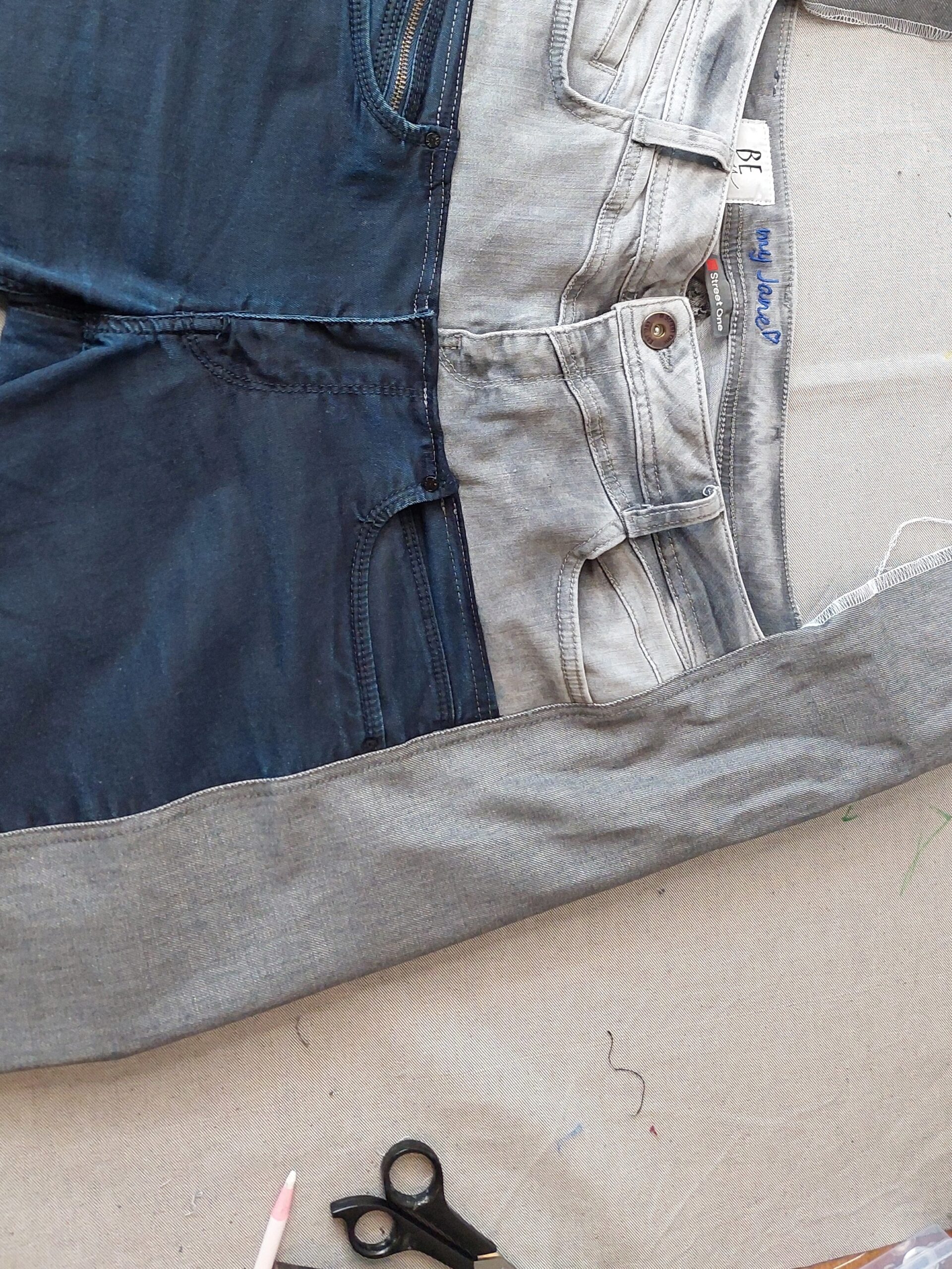 Upcycling oder Bearbeitung von drei Jeans auf einen Tisch, Schere vorhanden